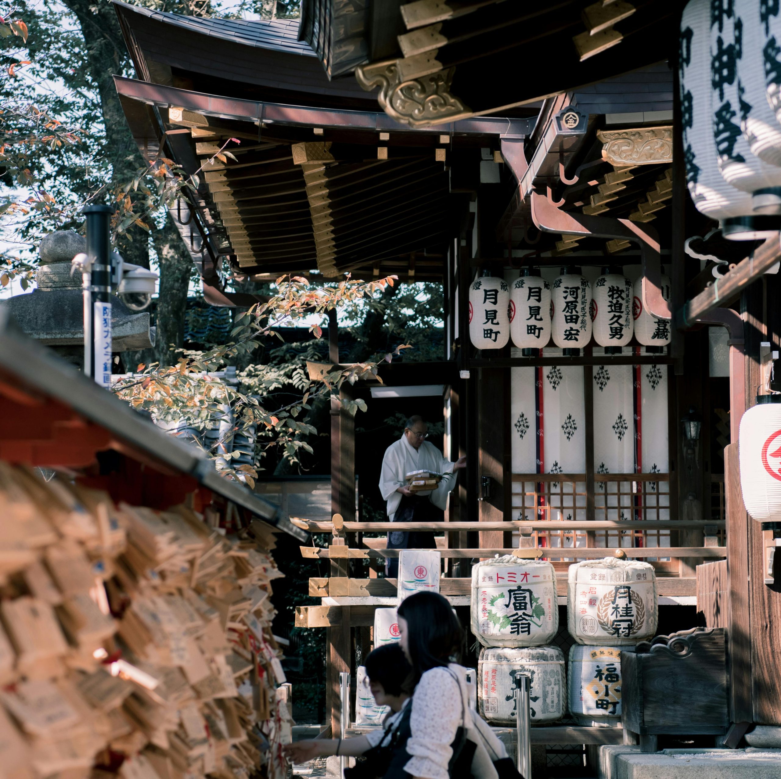 Tranquil scene at a Kyoto shrine with traditional lanterns and visitors exploring the site.